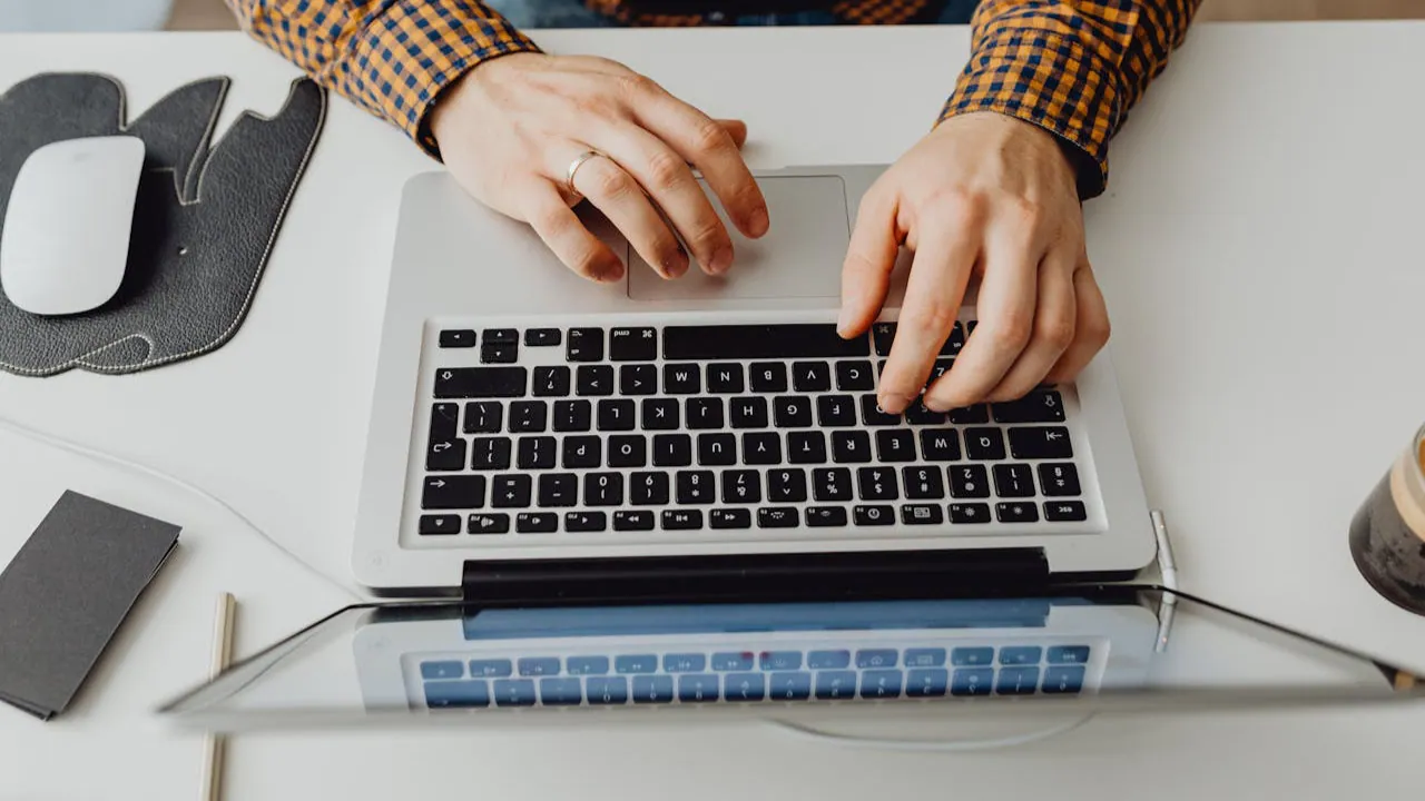 Homme en train de rédiger un texte sur un ordinateur.